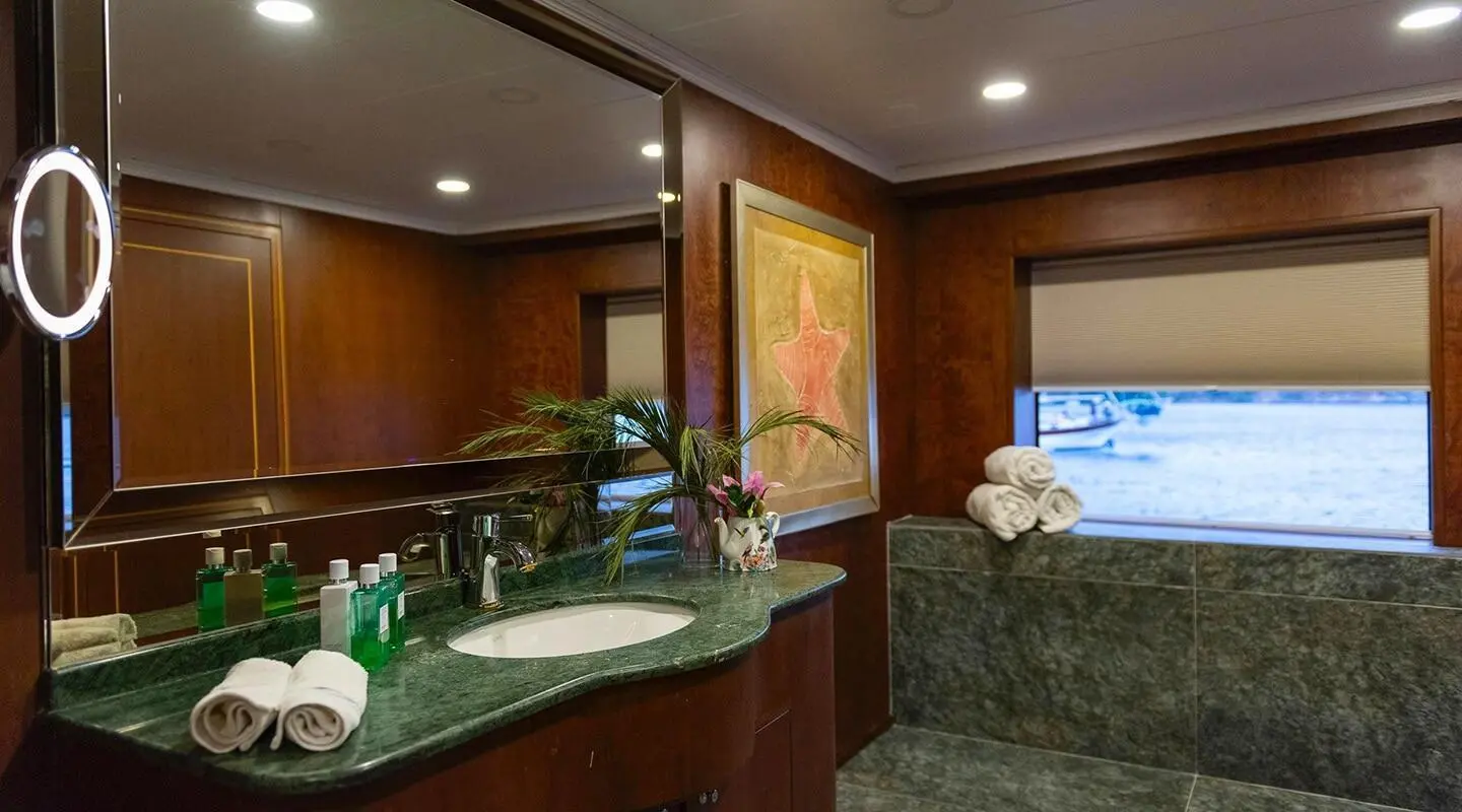Interior view of luxury yacht Ocean Breeze bathroom with sink, mirror, and warm lighting