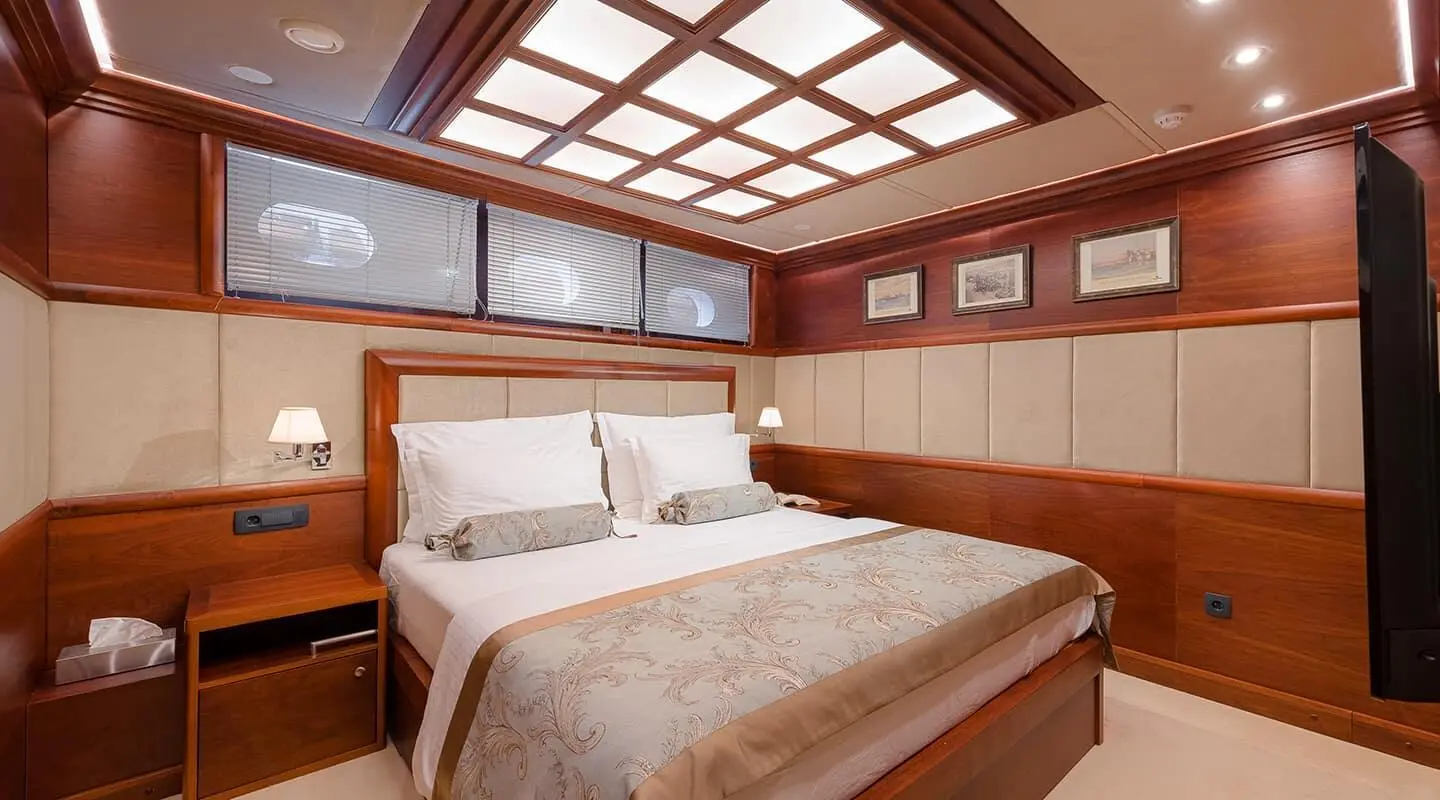 Wood-paneled luxury yacht cabin with upholstered headboard and windows
