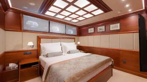 Wood-paneled luxury yacht cabin with upholstered headboard and windows