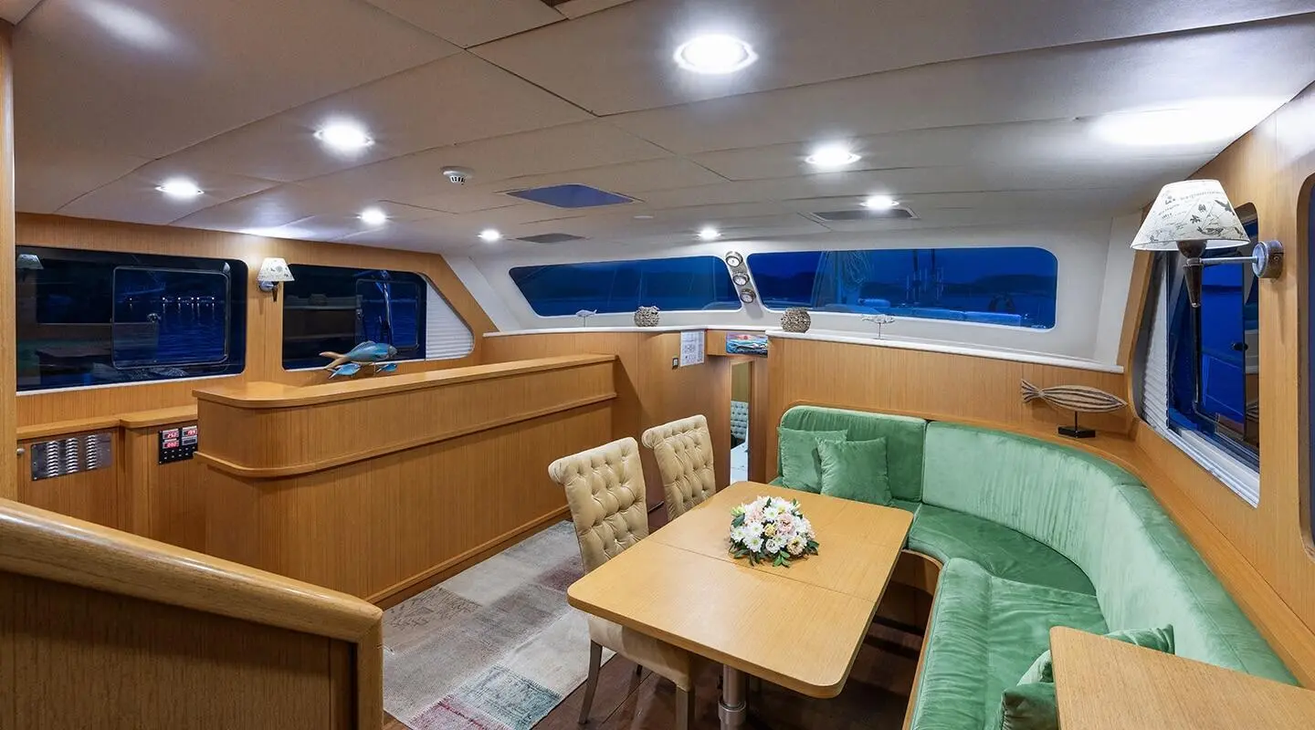 Artemis yacht charter cockpit seating area with wooden table and green cushions