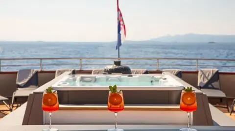 Yolo yacht on sun deck with seating and railings; sea and distant shore in background
