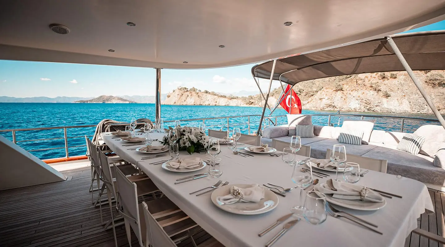 Queen Of Makri yacht with elegant dining setup on deck at sunset