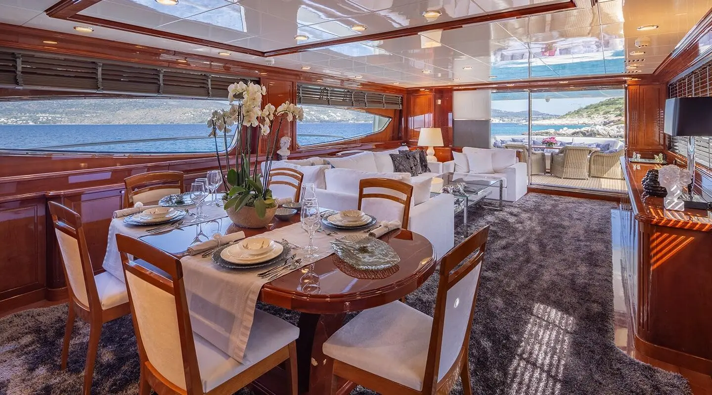 Dinner setup on a yacht deck with a table, chairs, and sunset in background