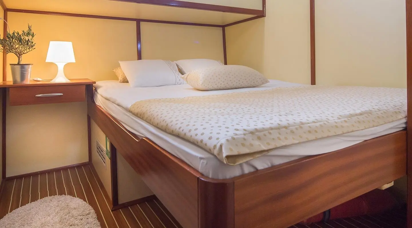 Altair yacht bedroom with neatly made bed and soft lighting