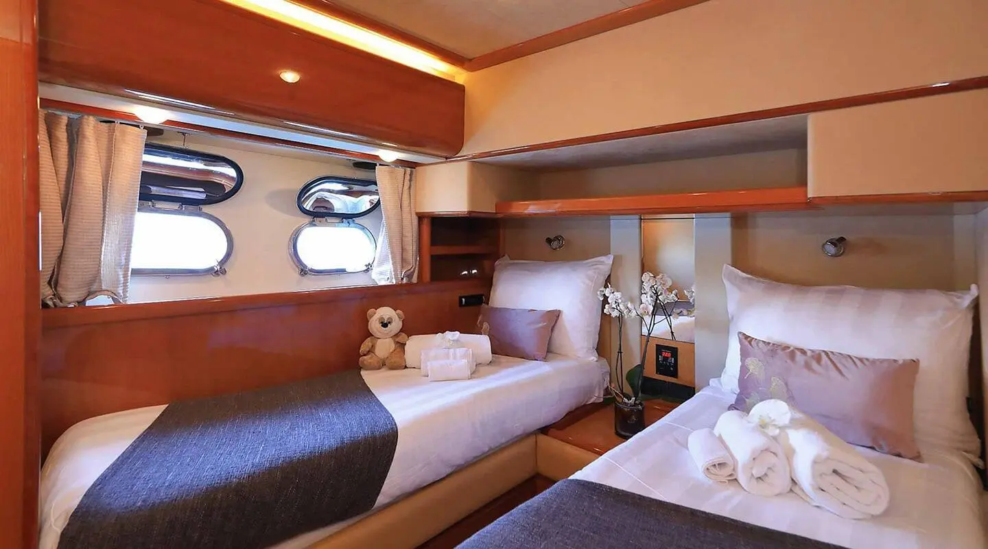Quo Vadis I yacht interior: two twin beds, wood cabinetry, soft lighting