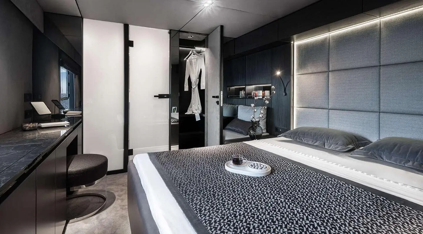 Alteya yacht interior with bed, navy-patterned bedspread, wardrobe, and seating