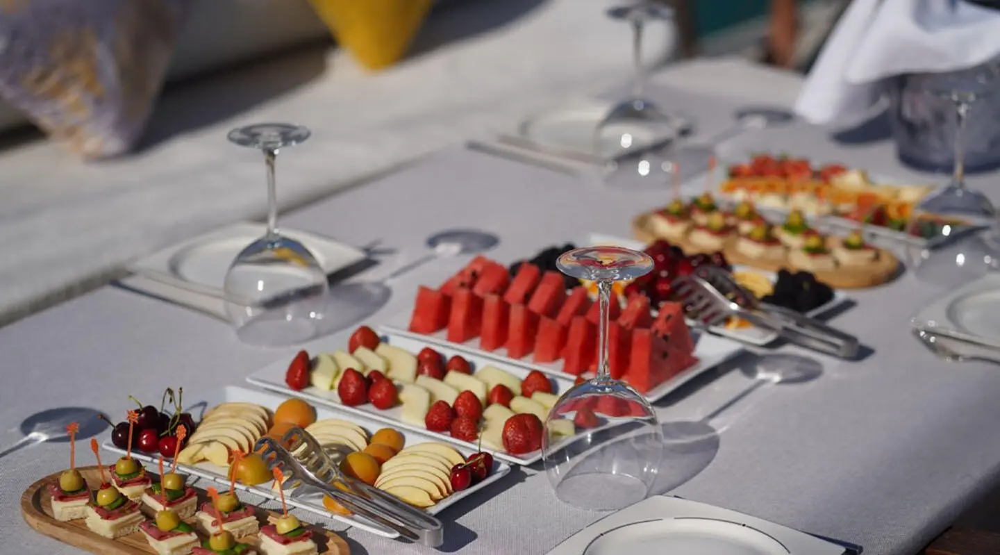Elegant dessert spread on a yacht table with red berries and pastries at sunset
