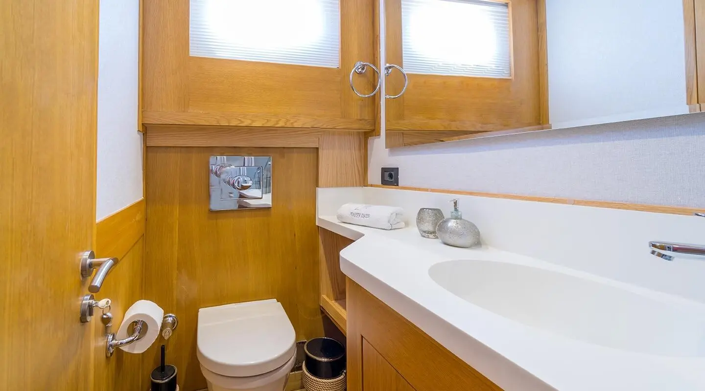 Interior view of a yacht head with wooden cabinetry, sink, mirrors, and toilet