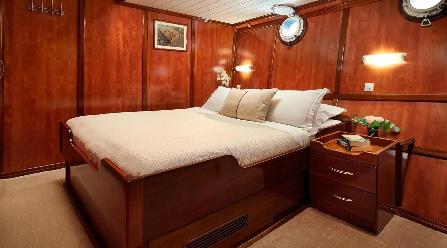 Cozy yacht bedroom with a large bed, wooden panels, and bedside lamps