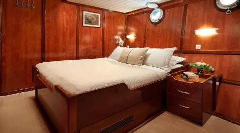 Cozy yacht bedroom with a large bed, wooden panels, and bedside lamps