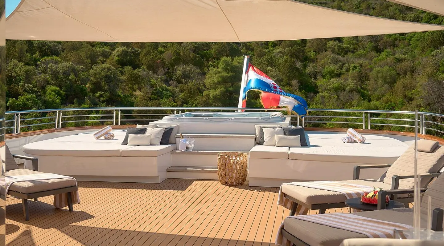 Sunset on deck of Cristal yacht with wicker seating and blue water