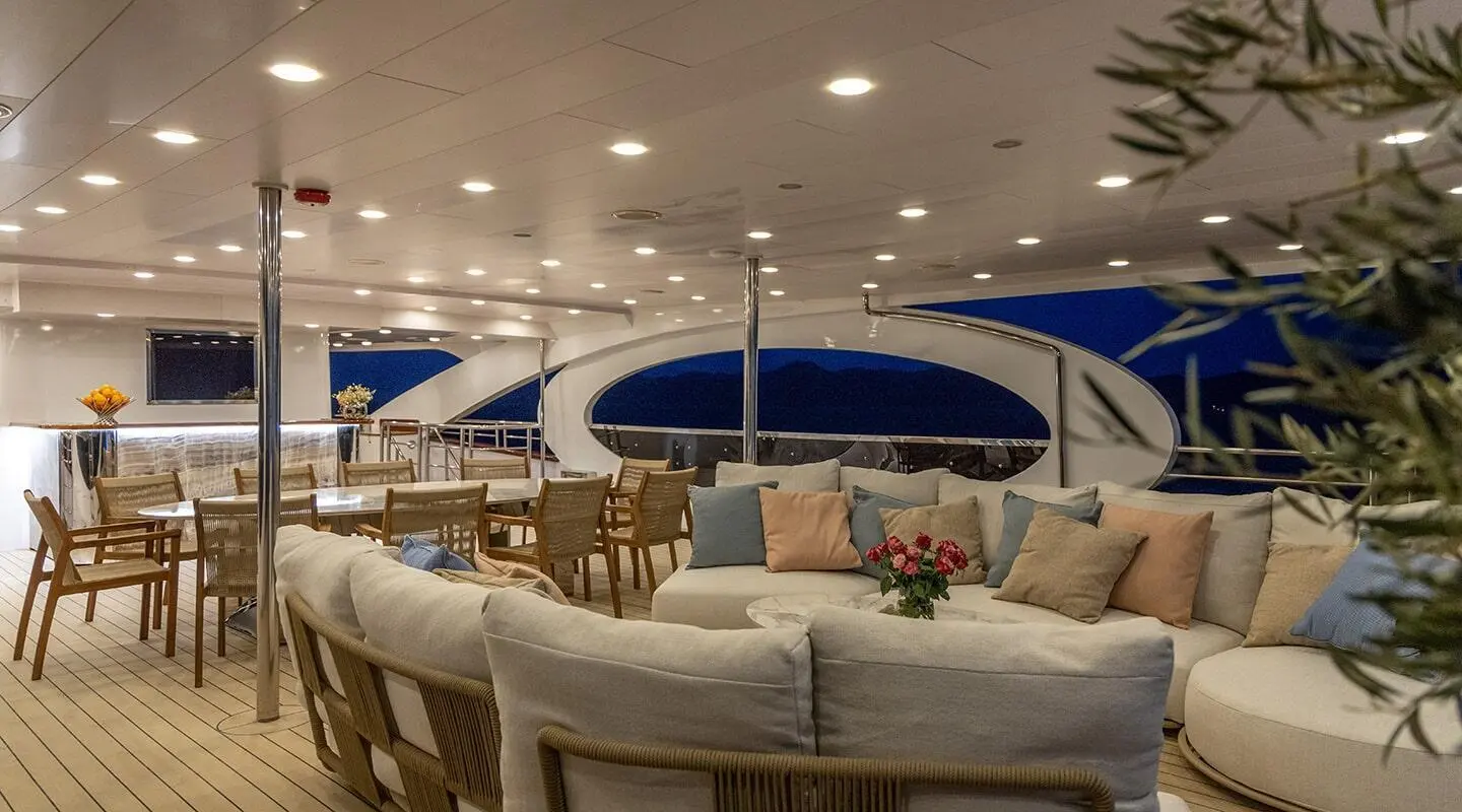 Olimp luxury yacht deck at sunset, seating area under blue canopies