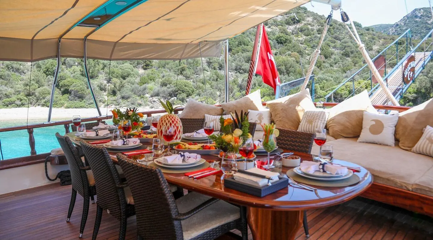 Aft deck of Ulucinar gulet with sun loungers, table set, and ocean view