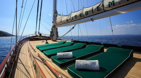 Carpe Diem 7 yacht deck with green seating and wooden rails at sunset