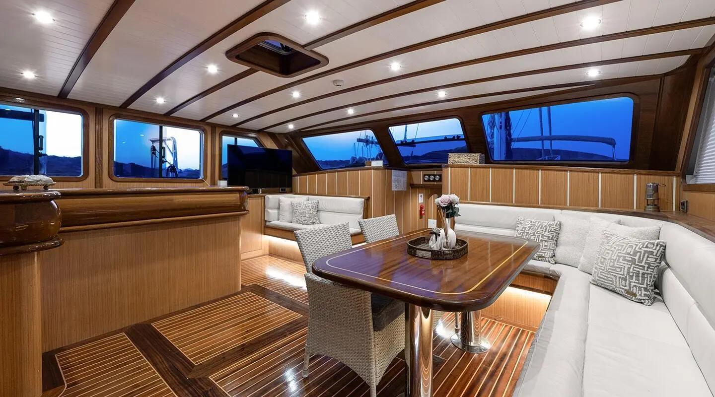 Sunset-lit yacht interior with teak deck, seating, and dining table aboard Gozdem The One