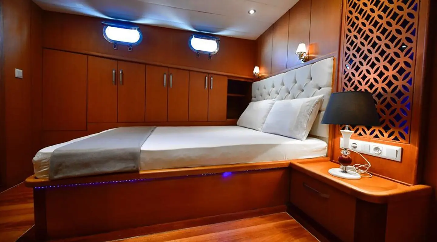 Blu Dream yacht cabin interior with double bed, wooden panels, and pillows