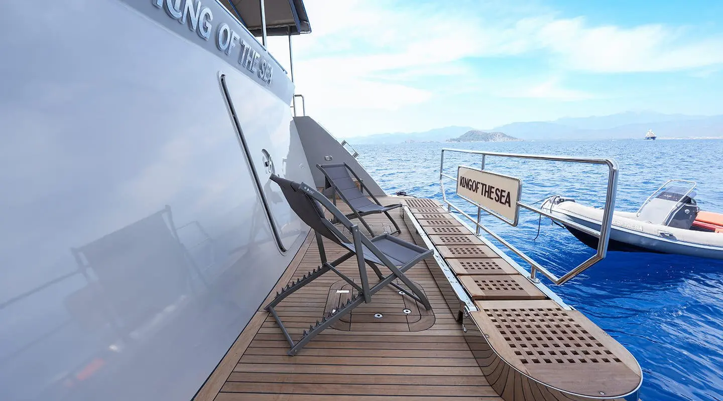 Sunset on a luxury yacht deck with seating and railings overlooking blue sea