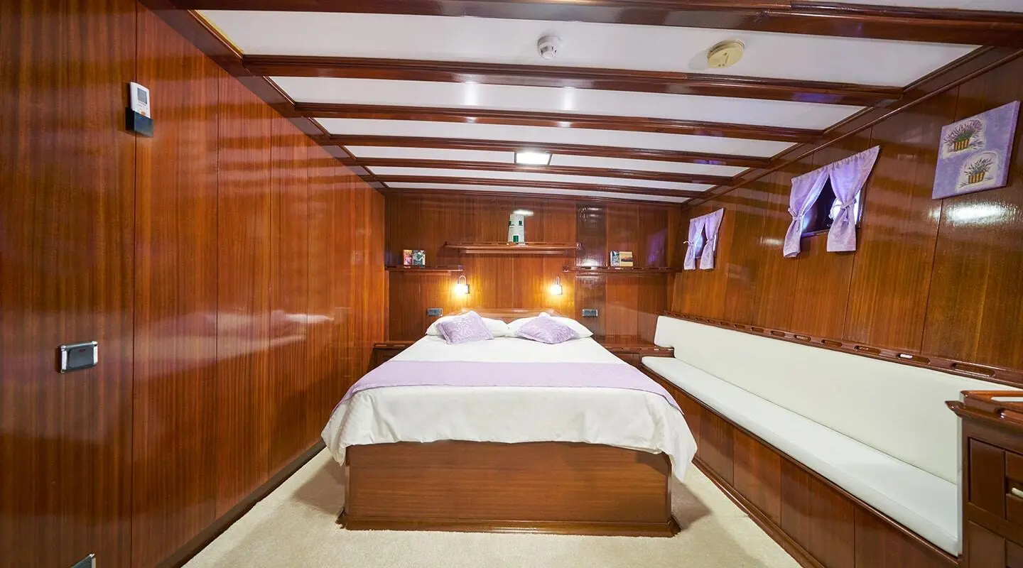 Stella Maris luxury yacht cabin with large bed, wood paneling, and warm lighting