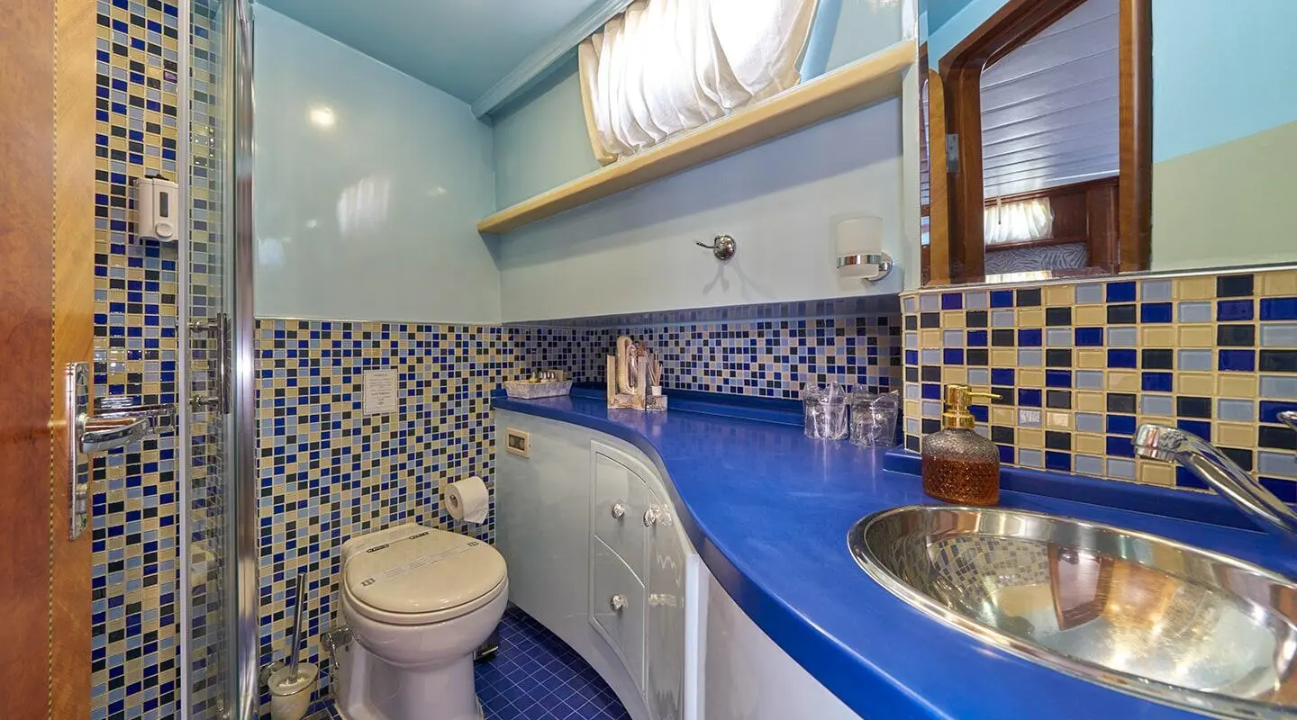 Interior bathroom aboard Lotus gulet, blue sink, tiled walls, fixtures