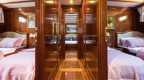 Wood-paneled cabin hallway with two side bedrooms and beds