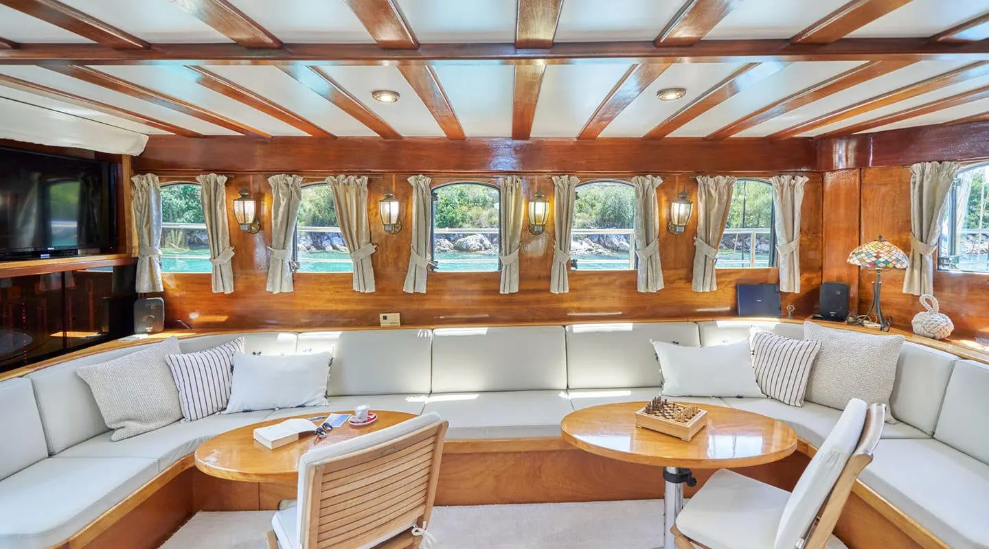 Inside a gulet Libra salon with wooden beams, cushioned seating, and windows