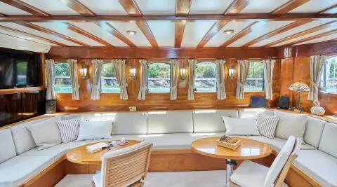 Inside a gulet Libra salon with wooden beams, cushioned seating, and windows