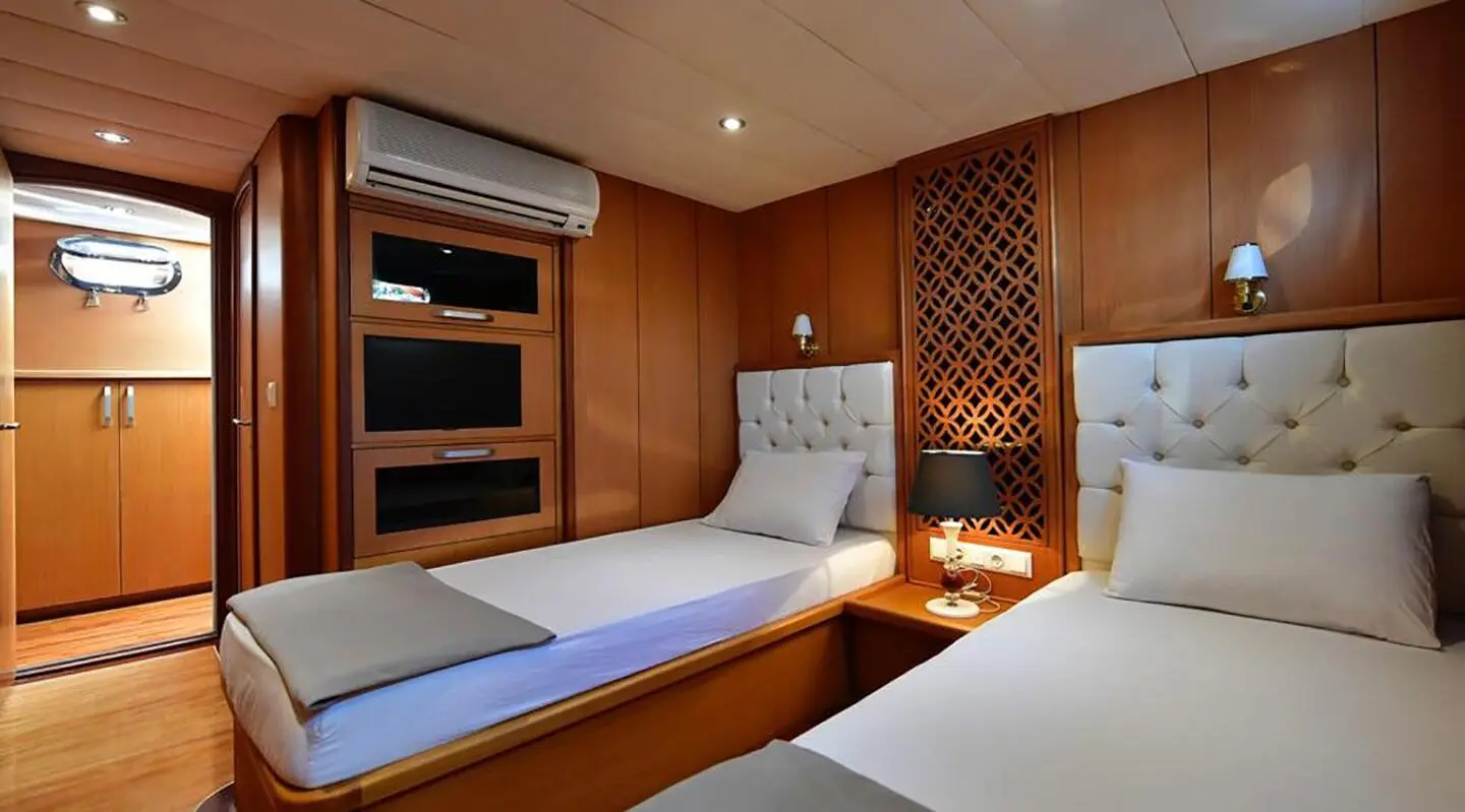 Cozy yacht cabin with wooden panels, bed, and built-in shelves onboard Blu Dream