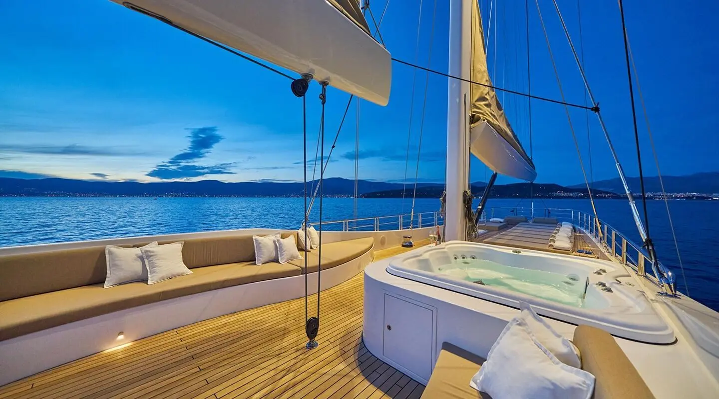 Sunlit yacht deck of Acapella with seating, railing, and ocean view at sunset