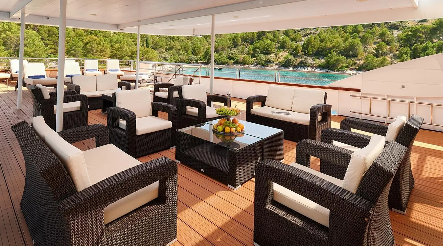 Queen Eleganza upper deck lounge with wicker chairs and table seating