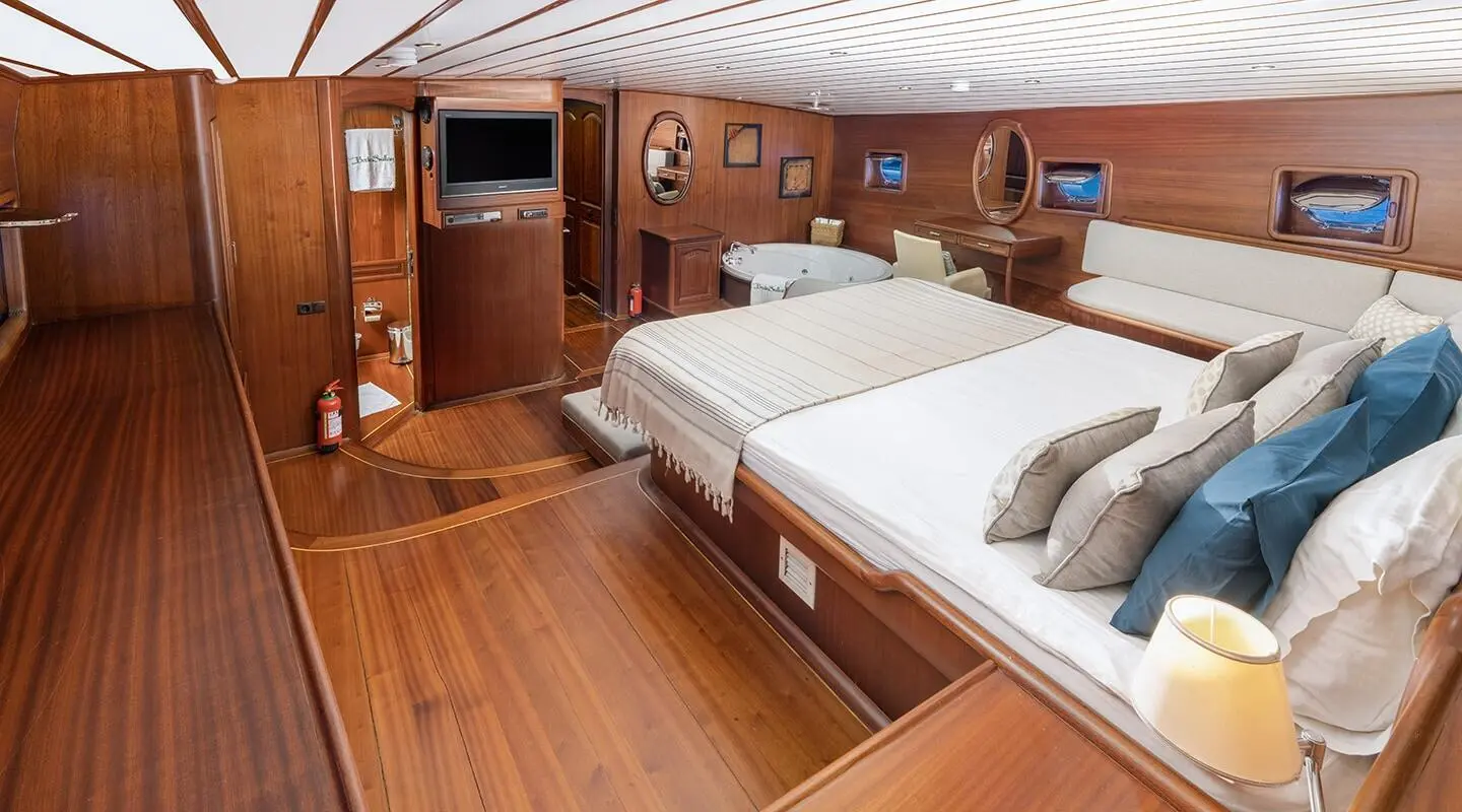 Sunset-lit luxury gulet interior with wooden deck, two beds on yacht Bedia Sultan