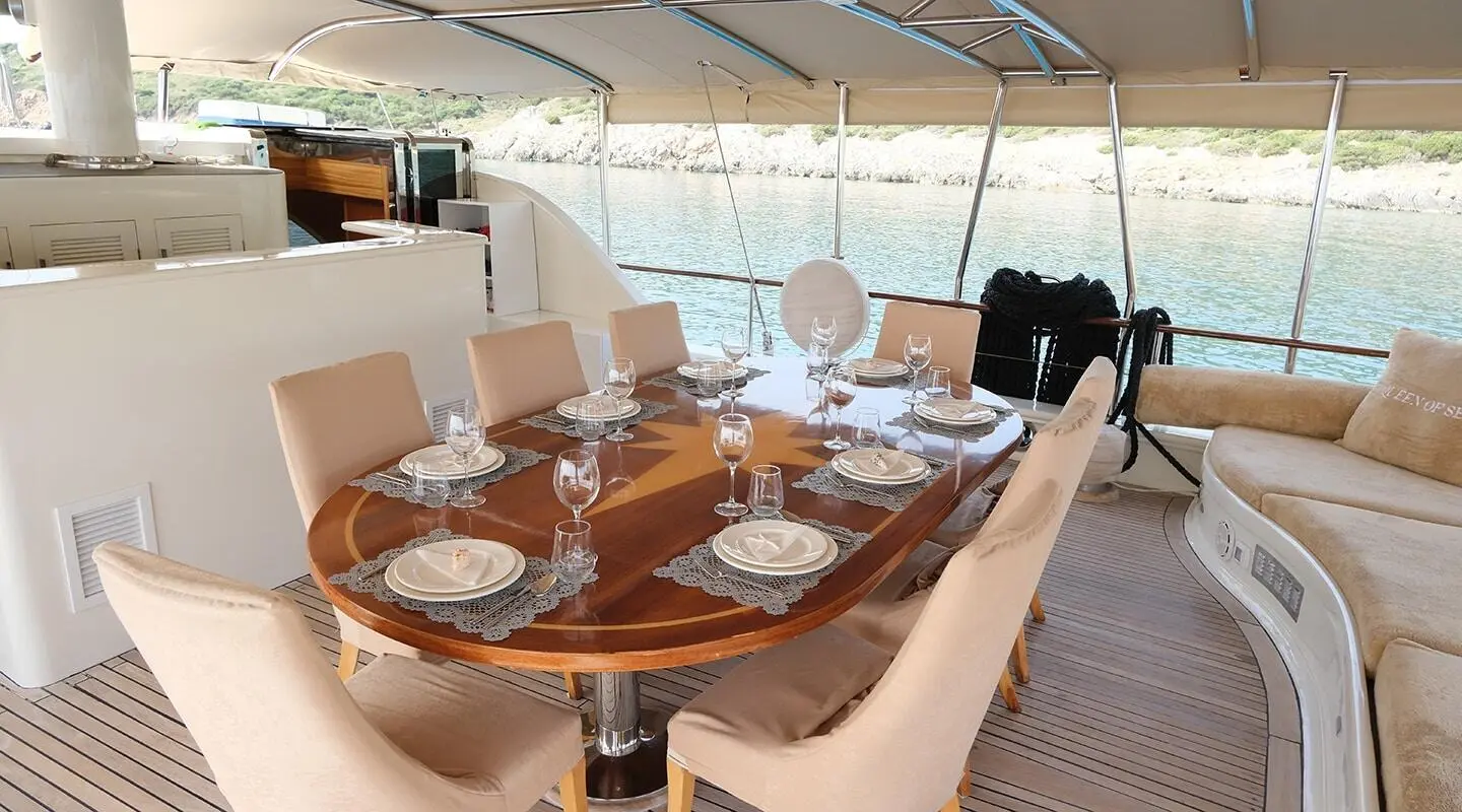 Queen Of Sea yacht charter interior dining area with table set for guests at sunset
