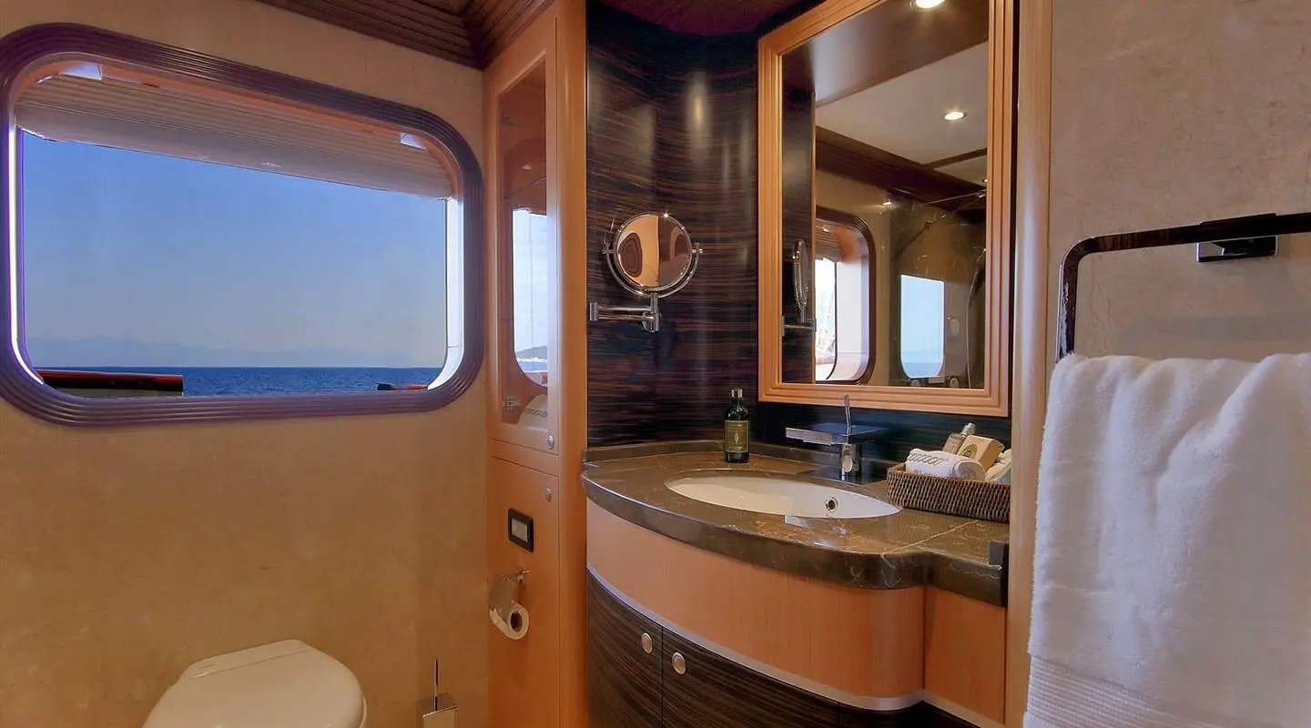 View of a luxury yacht bathroom with wooden cabinets and mirror sink area