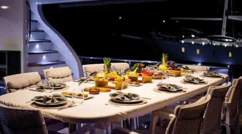 Queen Of Makri yacht at dusk with a long dining table set for guests on deck