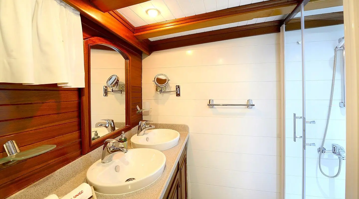 Sunset aboard Ecce Navigo: luxury yacht with white deck, sails, and calm blue sea