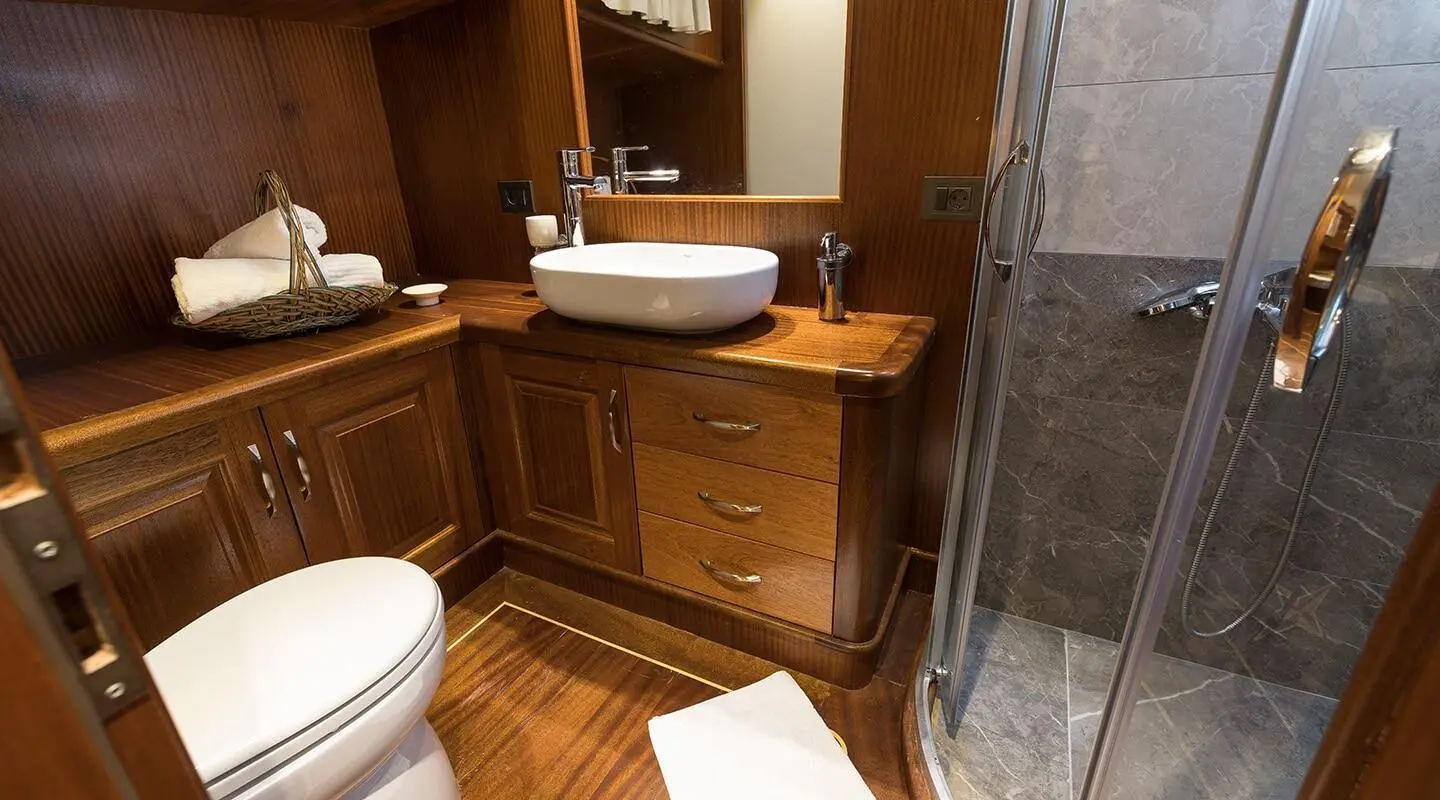 Luxurious yacht bathroom with wood cabinetry, sink and shower enclosure