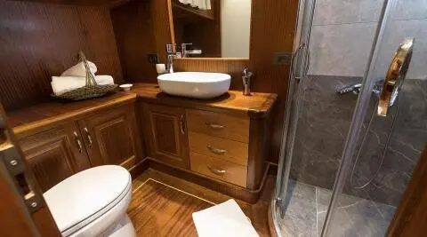 Luxurious yacht bathroom with wood cabinetry, sink and shower enclosure