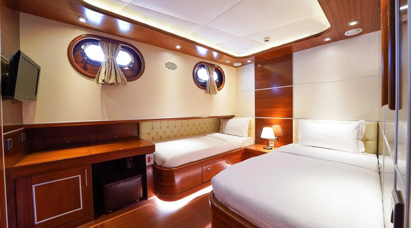 Interior of La Bella Vita yacht showing bed, seating, cabinets, and warm lighting