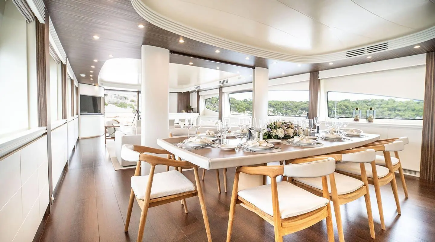 Pareaki II yacht dining area with sunset light, wooden table and chairs