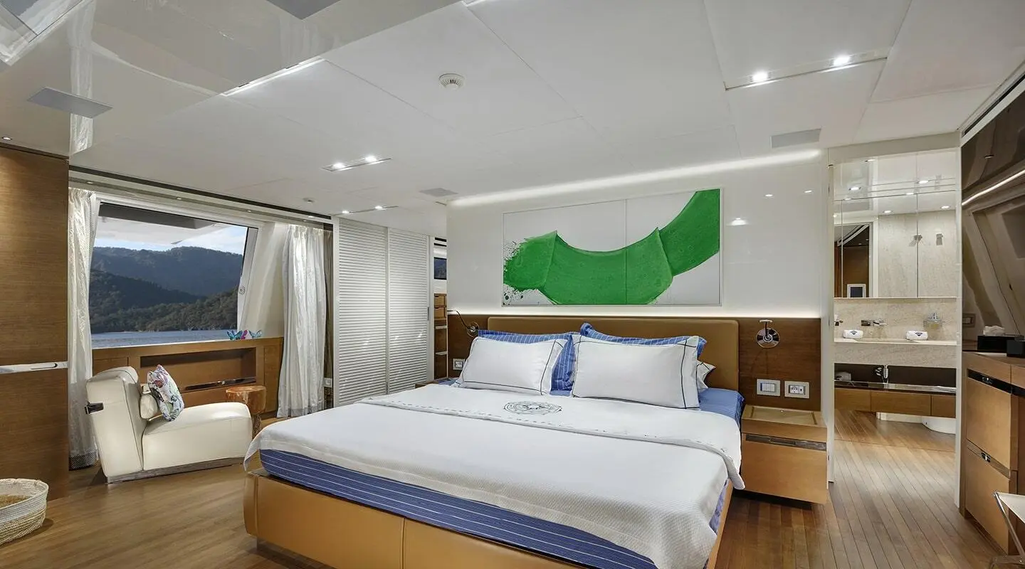 Morning Star yacht master bedroom with large bed, white bedding, wood accents, and soft lighting.