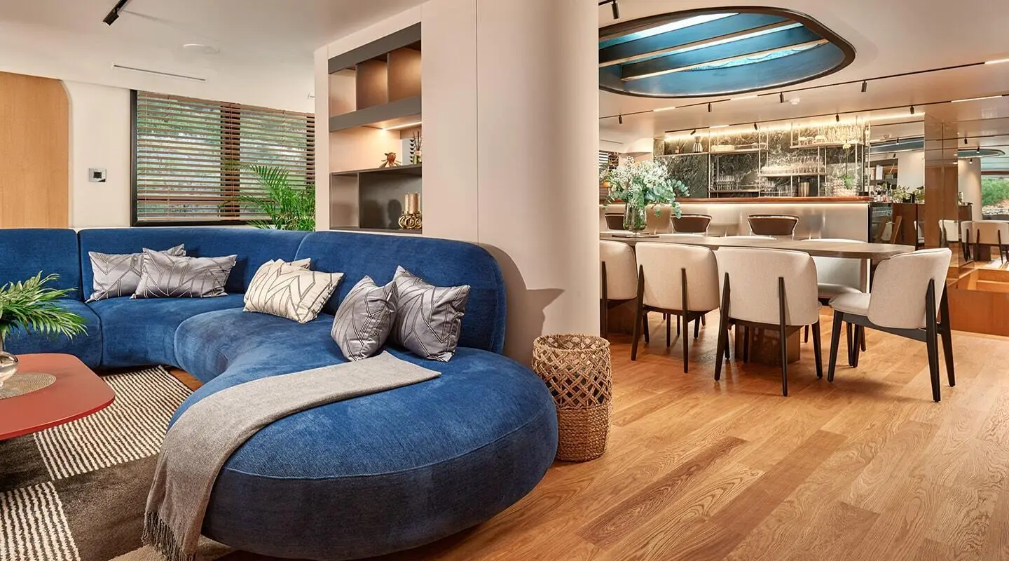Inside lounge of Anetta motor yacht, round blue sofa, wooden floor, framed art