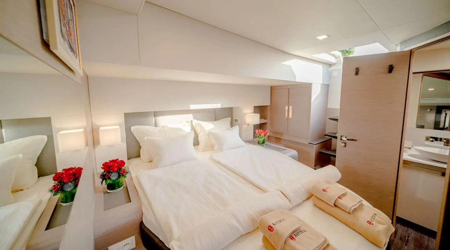 Astoria motor yacht cabin with two single beds, white linens, and bedside tables