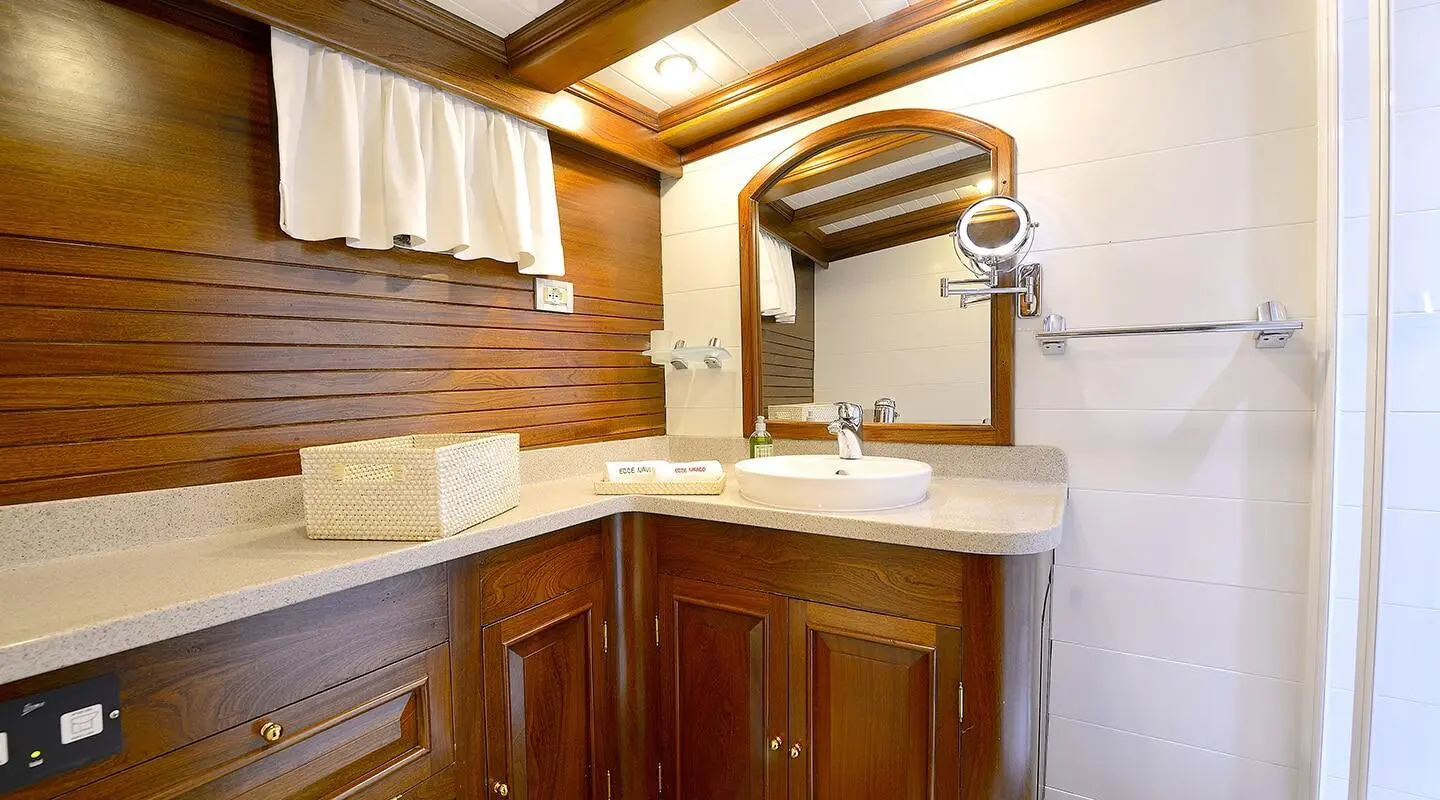 Ecce Navigo gulet bathroom with wooden cabinets, white sink and mirror cabinet