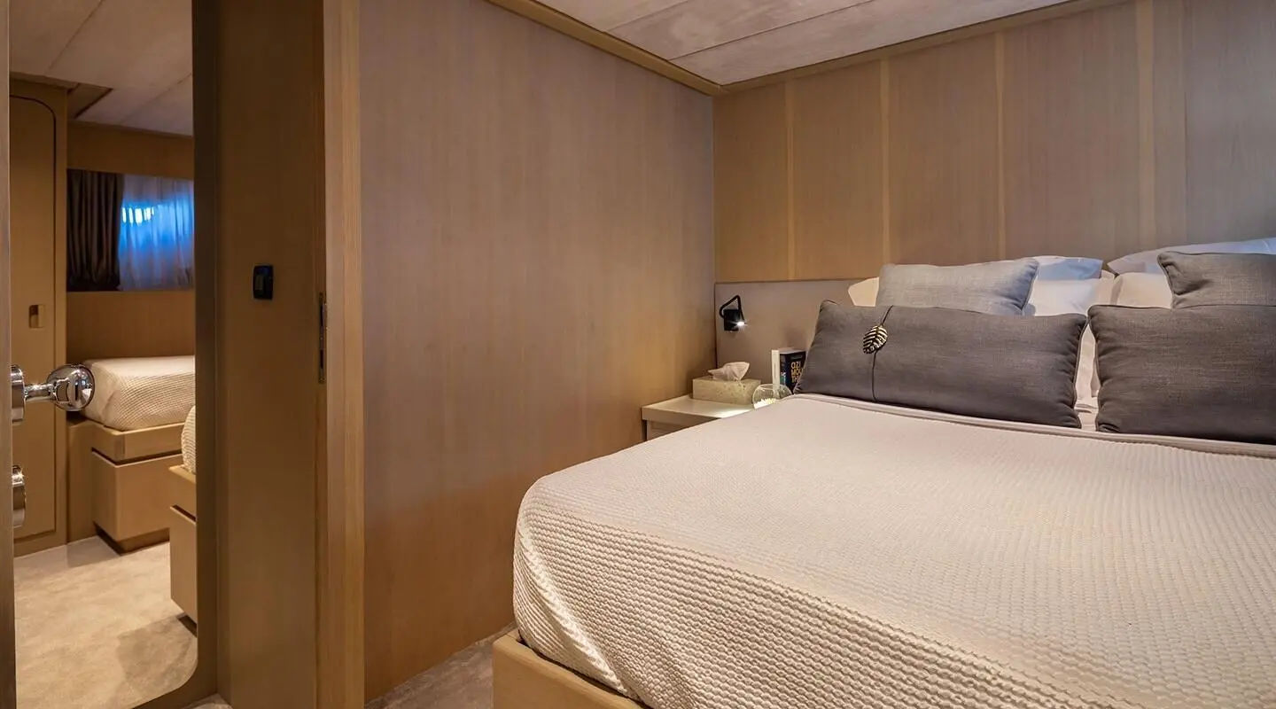 Luxurious yacht cabin with large bed, wooden paneling, and bedside lamps