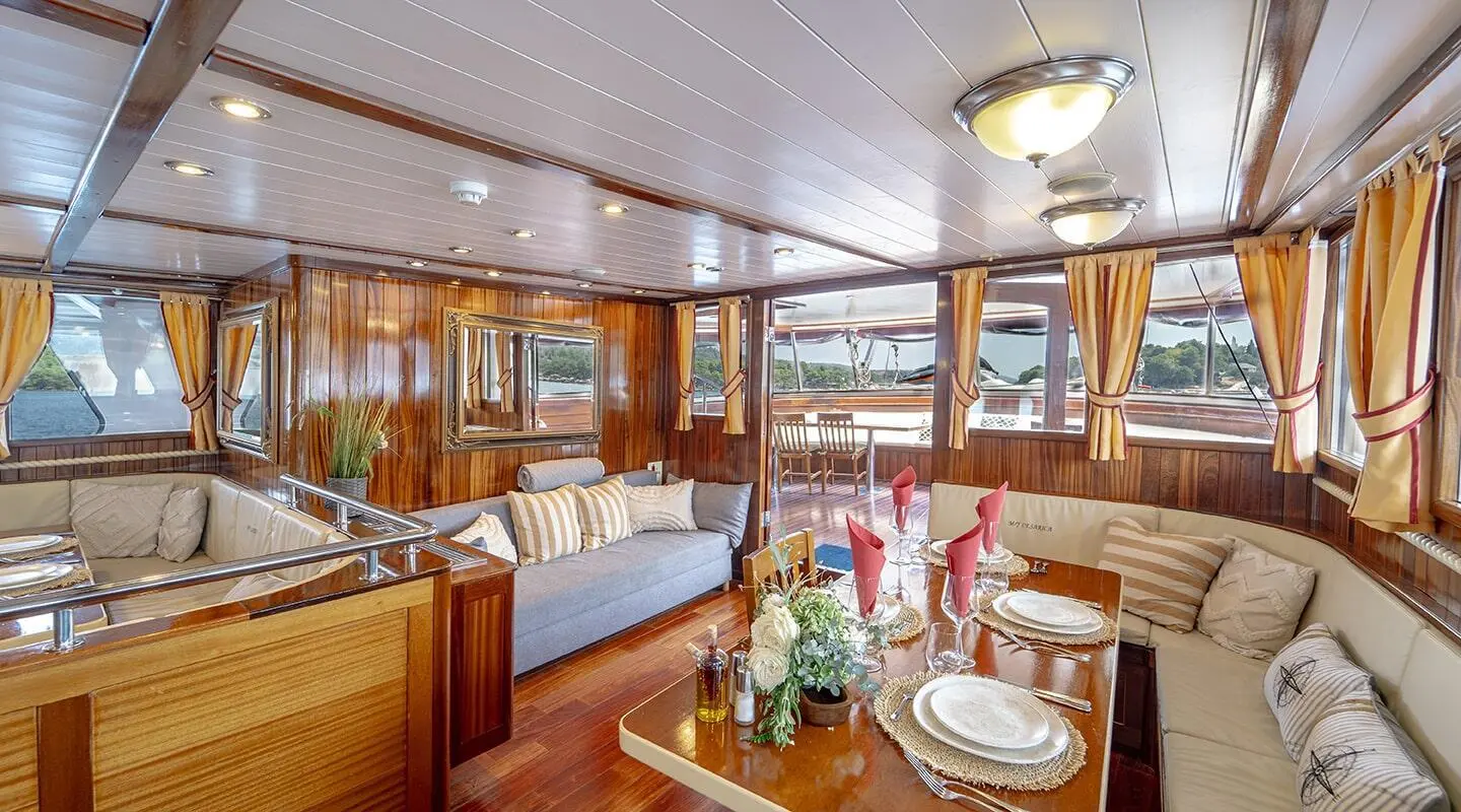 Cesarica yacht interior with polished wood, dining setup, and windows