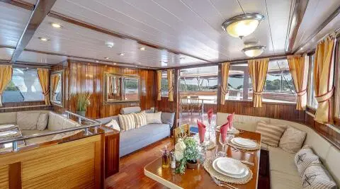 Cesarica yacht interior with polished wood, dining setup, and windows