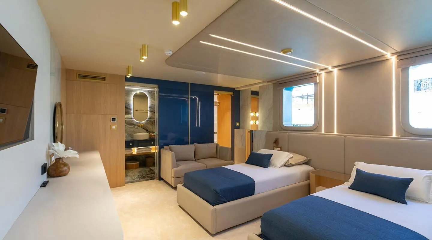 Interior of Scorpios yacht with blue and white bedding, seating, and ambient lighting