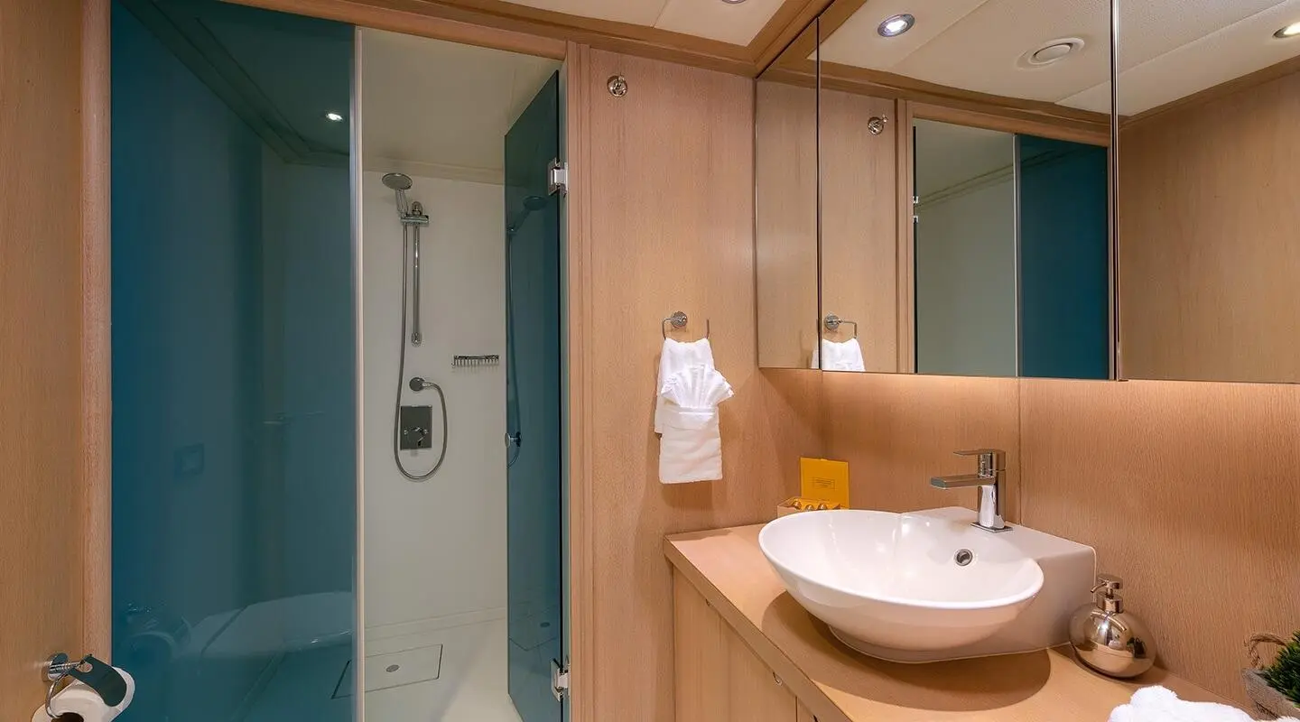 Shower cabin and sink area with wooden cabinets and mirrors on Grace yacht