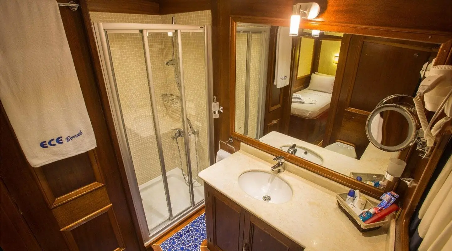Yacht Ece Berrak seen from aft, warm cabin lights illuminating marble sink area