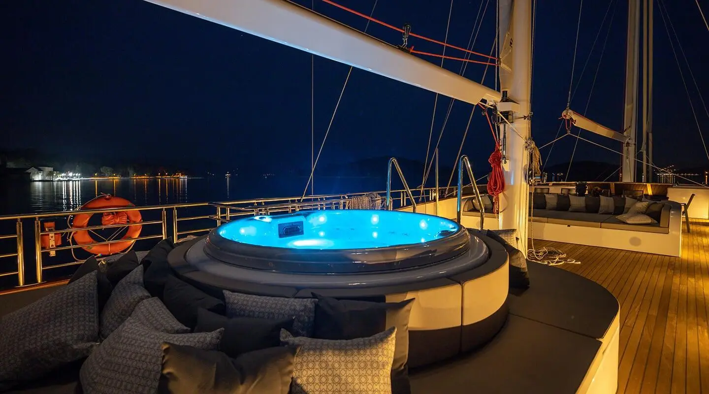 Love Story yacht with blue circular hot tub on deck at dusk