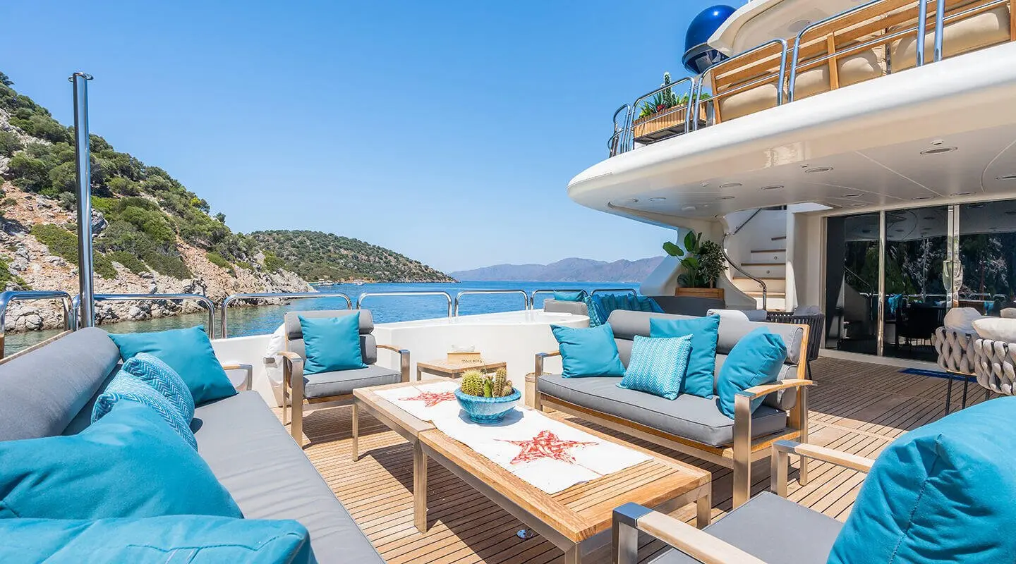 Amadea yacht deck at sunset with blue cushions and lounge chairs
